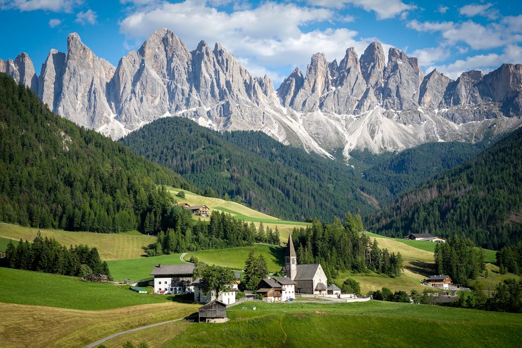 Picturesque village with Dolomites backdrop on a sunny day, ideal for nature photography.