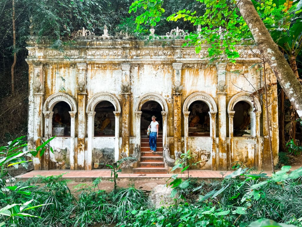 Moss-covered stone structure with multiple arches hidden in the forest at Wat Pha Lat.