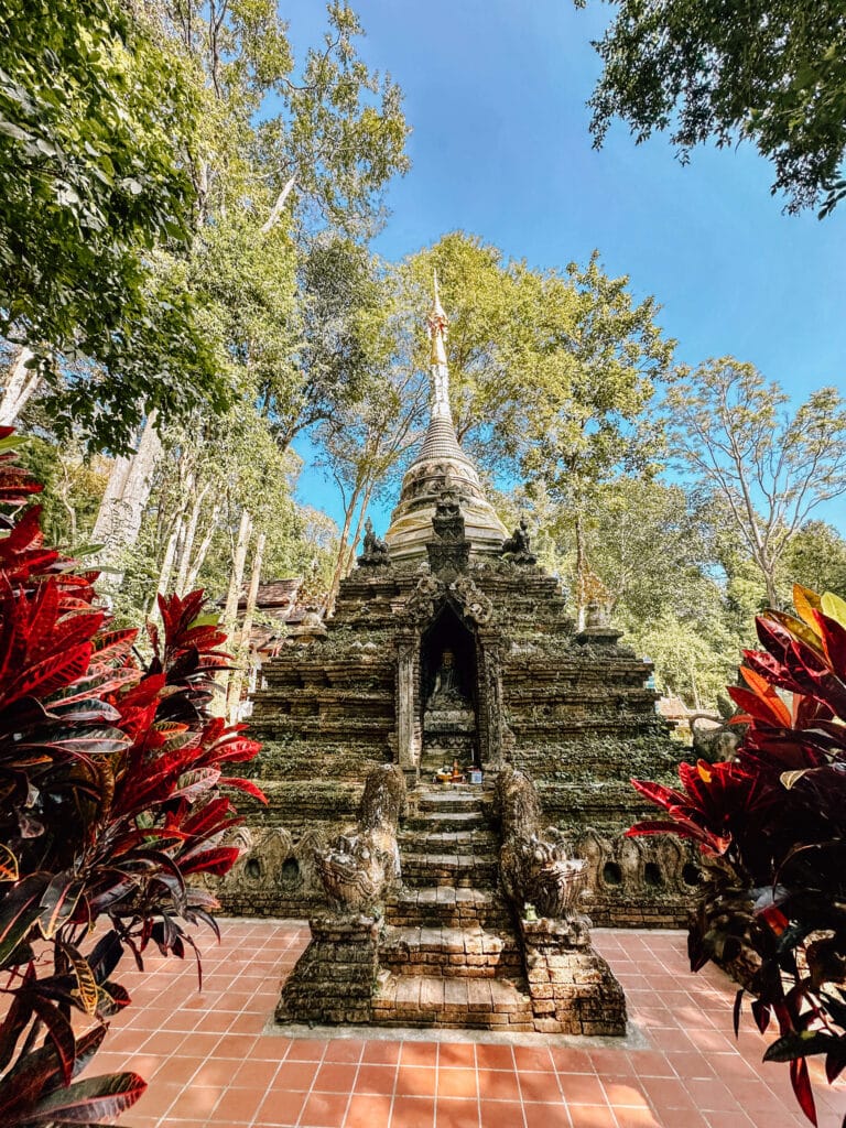 Steep monument lined with red foliage leading to a shrine at Wat Pha Lat.
