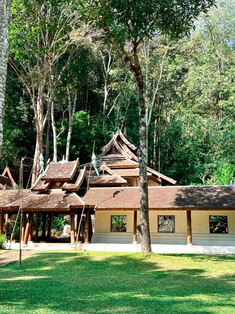 Wooden temple structure with sloping roof nestled in the forest at Wat Pha Lat.