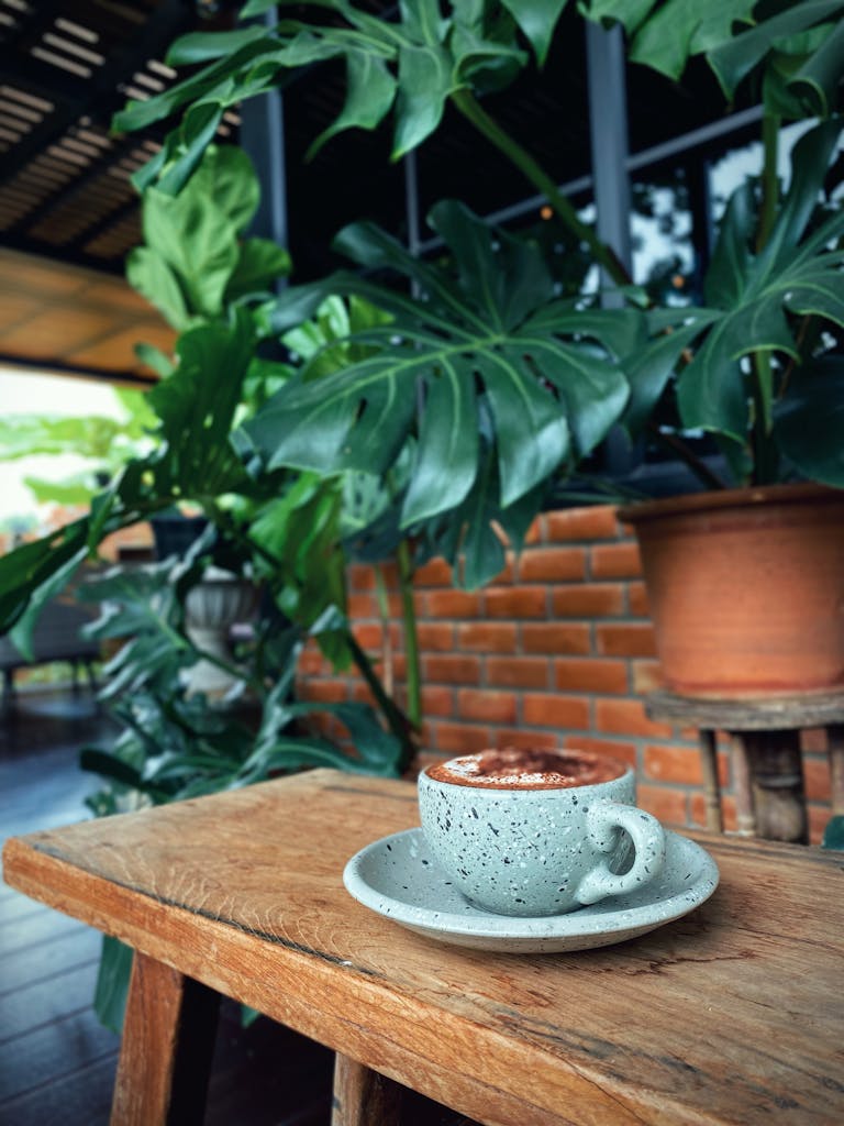 A serene coffee experience amid lush green plants in a stylish Thai cafe setting.