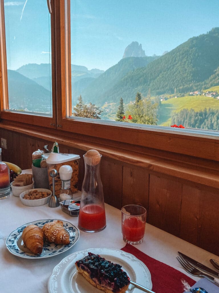 Morning breakfast at Bnb Lavi with pastries, juice, and mountain views through a large picture window.