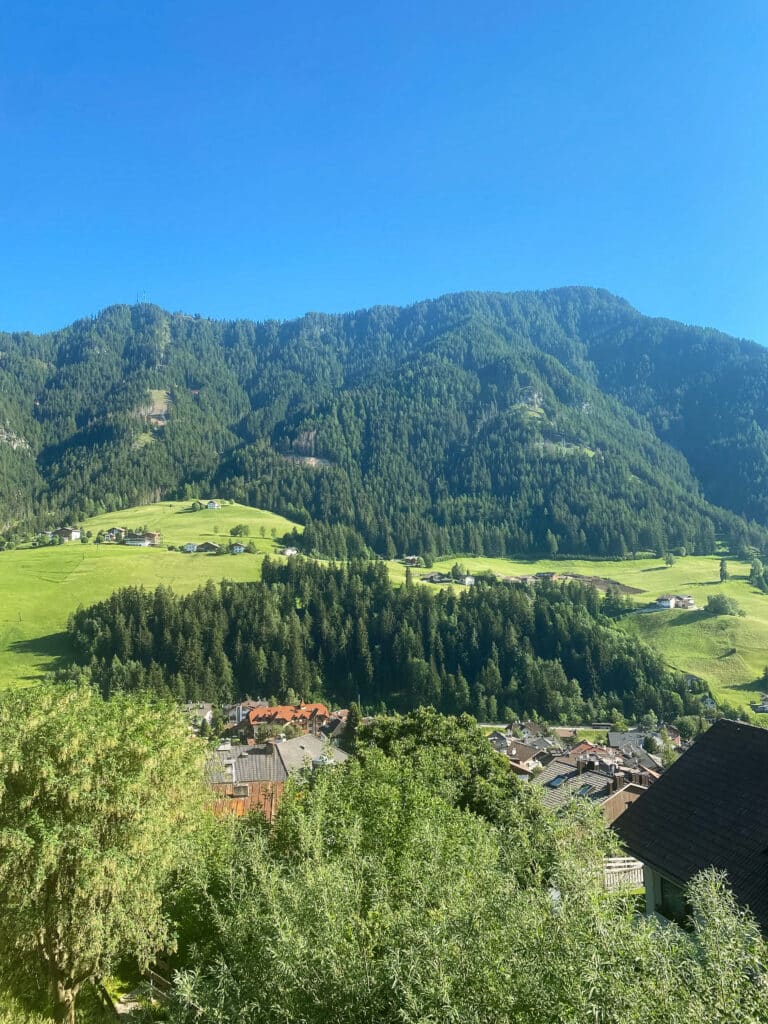 View of Ortisei village and green Dolomites valley from Bnb Lavi balcony on a clear summer morning.