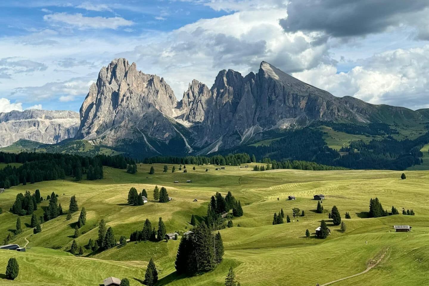 Breathtaking summer landscape of the Dolomites with lush green fields and dramatic mountains.