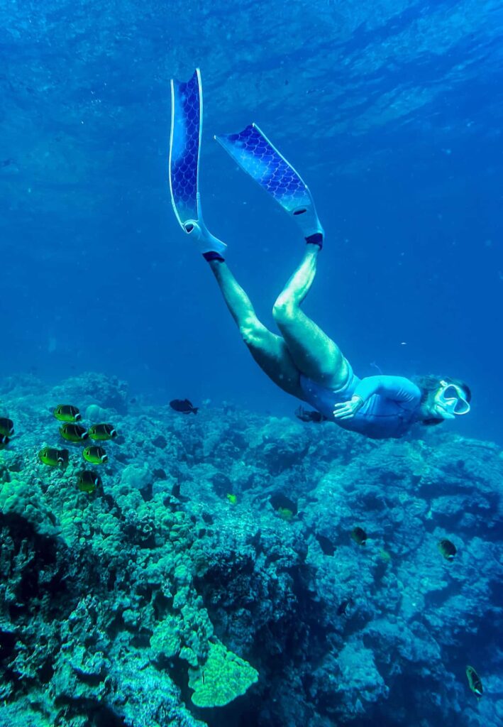 A snorkeler gliding above the reef at Kealakekua Bay, surrounded by deep blue water.