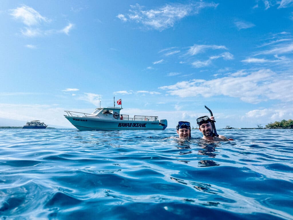 A small sportfishing-style snorkel boat idling near the shoreline at Kealakekua Bay.