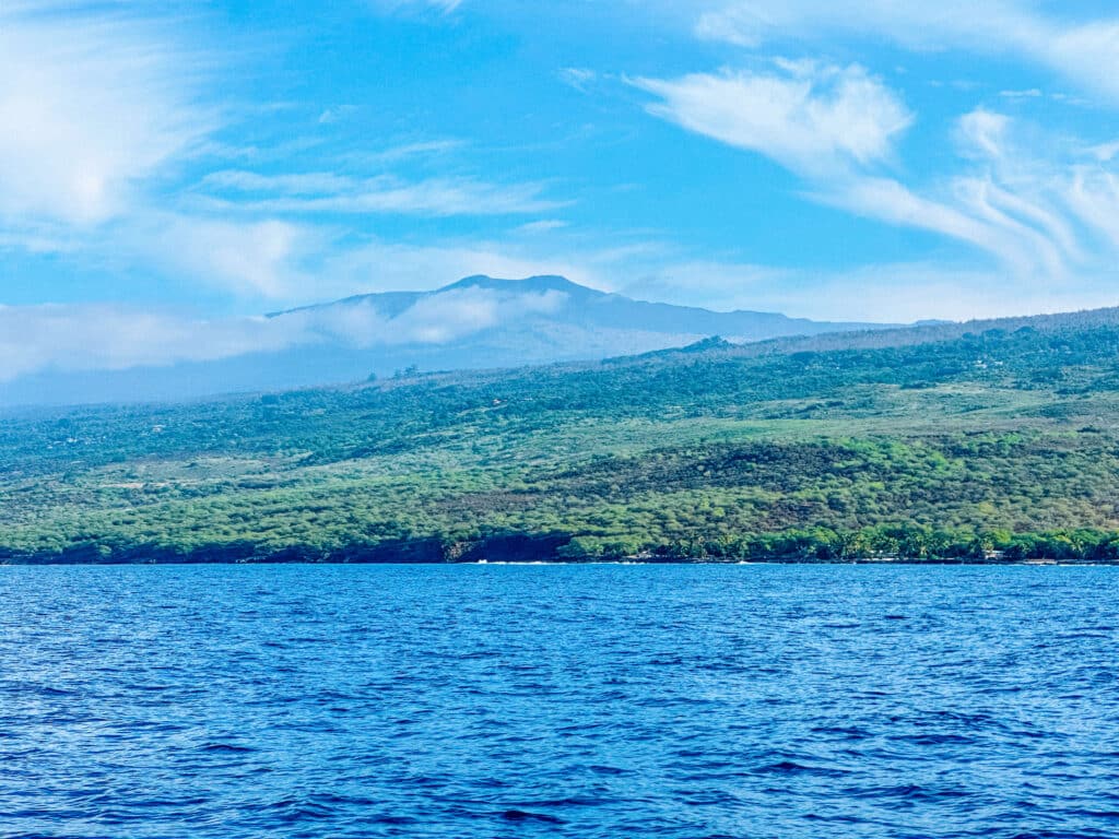 A wide view of the Kona coastline and calm ocean water on the approach to Kealakekua Bay.