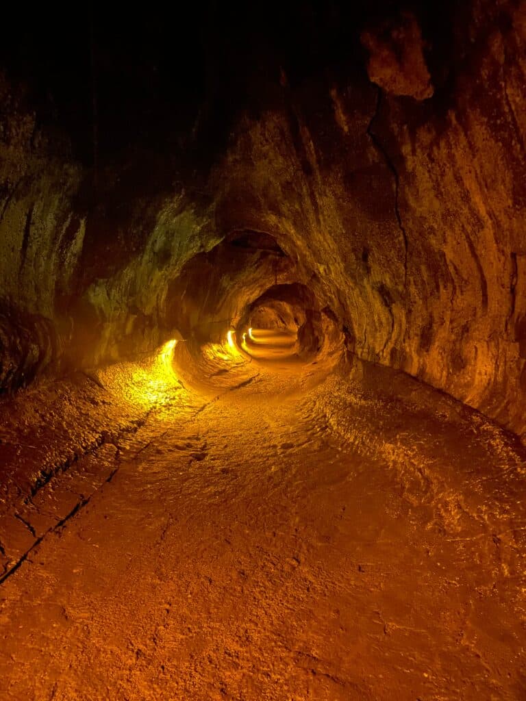 Interior view of the Nahuku Lava Tube with a lit pathway and uneven floor