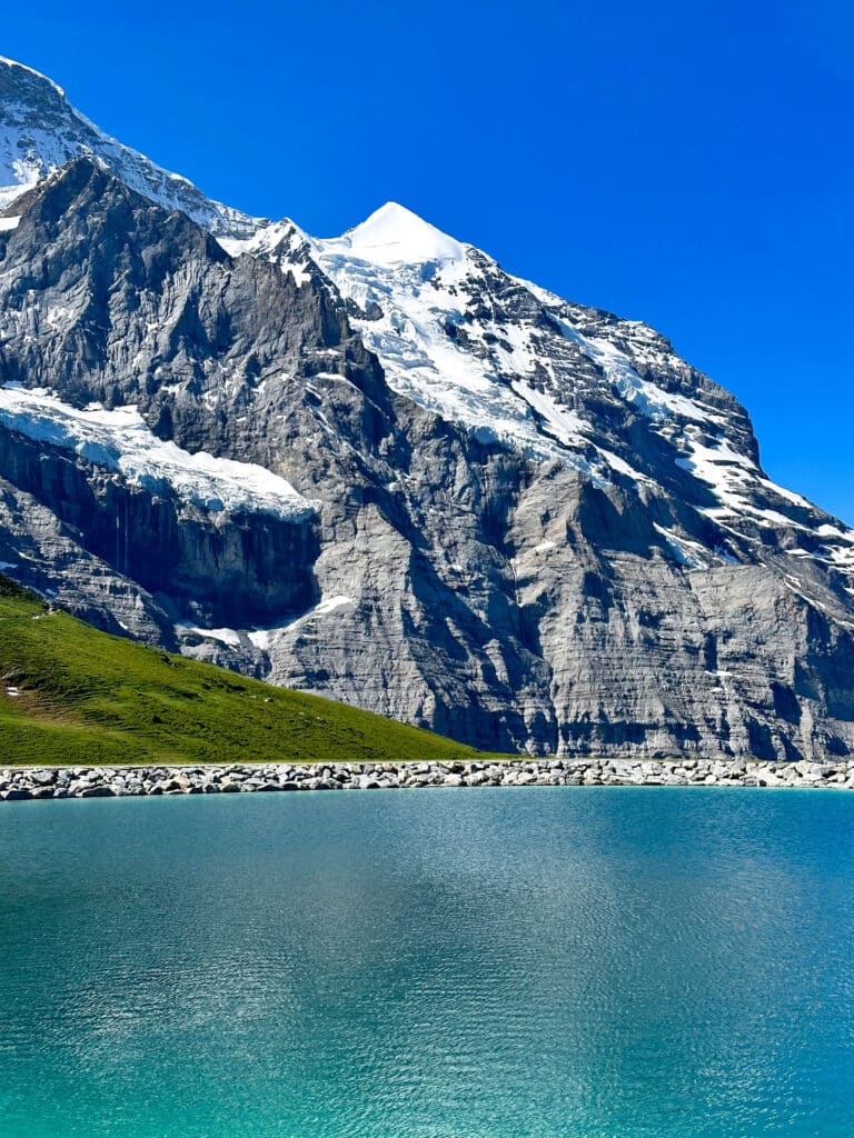 Clear blue water of Fallbodensee Lake beneath the dramatic North Face of the Eiger
