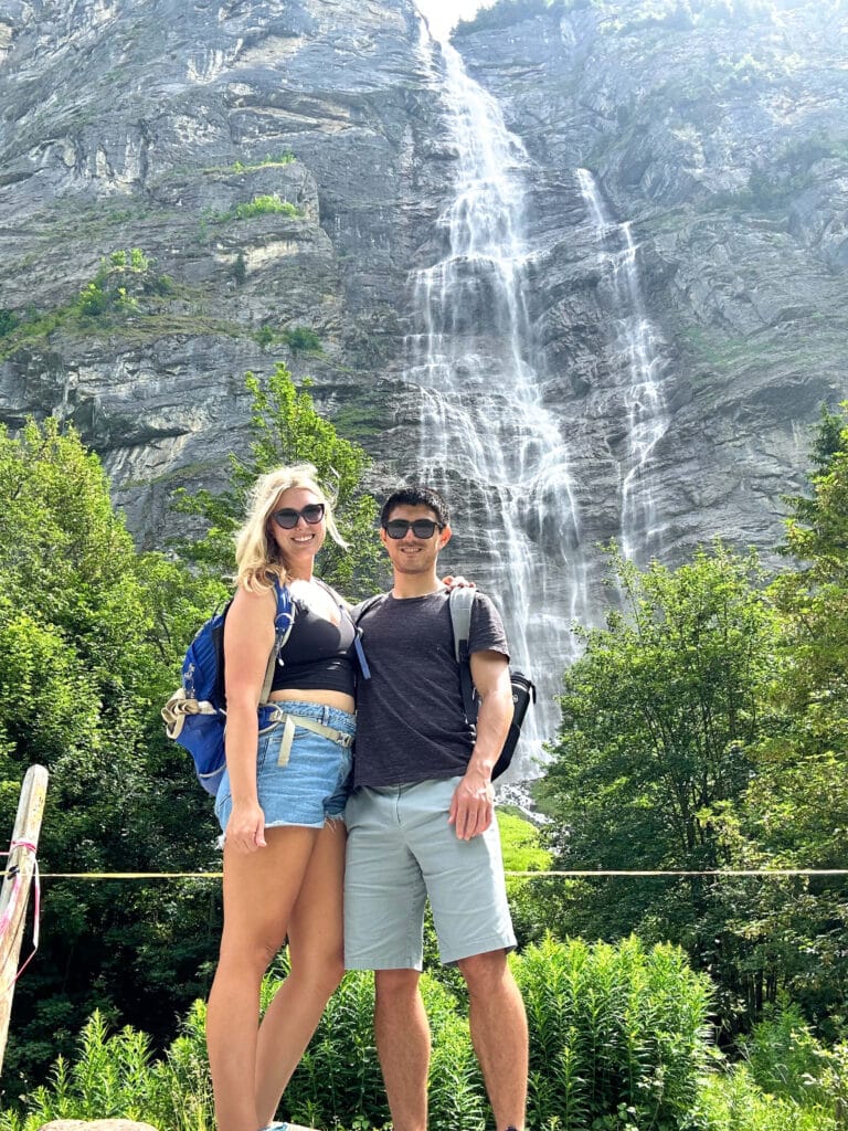 Two hikers standing at the base of a waterfall along the Lauterbrunnen Valley walking trail