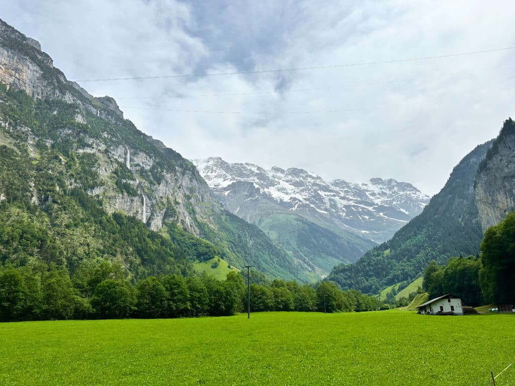Wide view of the Lauterbrunnen Valley with green meadows, towering cliffs, and distant waterfalls