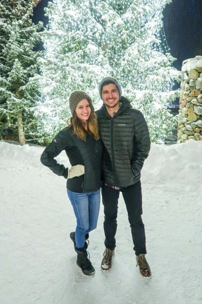 Friends posing under glowing Christmas lights on Breckenridge’s snowy main street.