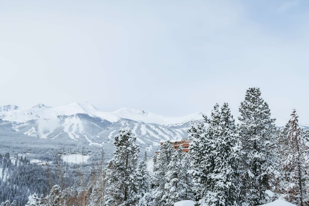 View of Breckenridge’s ski slopes covered in untouched snow and lined with pines.