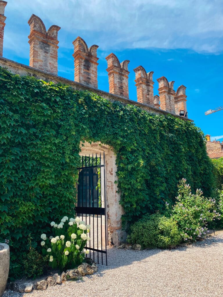Exterior castle like wall of the Giardino Giusti covered with vines, with a small doorway with an iron gate.