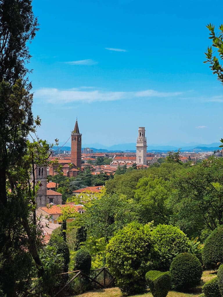 Panoramic view of Verona's rooftops and bell towers from the Giusti Garden belvedere, with cypress trees in the foreground