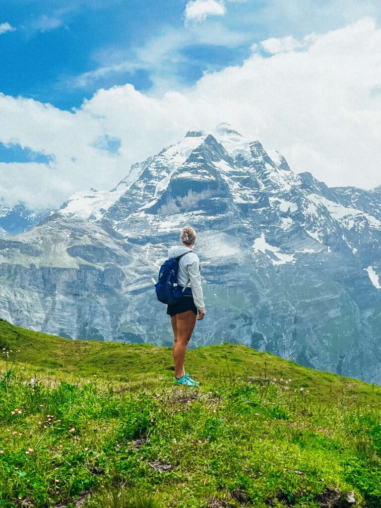 Hiker in front of a grand snowy mountain along the Northface Trail in Murren