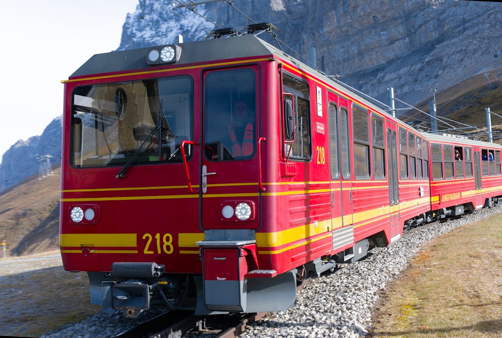 Red mountain train traversing the scenic Jungfraujoch landscape on a clear day.