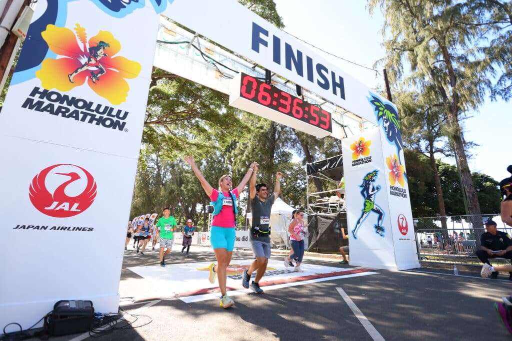 Two happy runners crossing the finish line of the Honolulu Marathon
