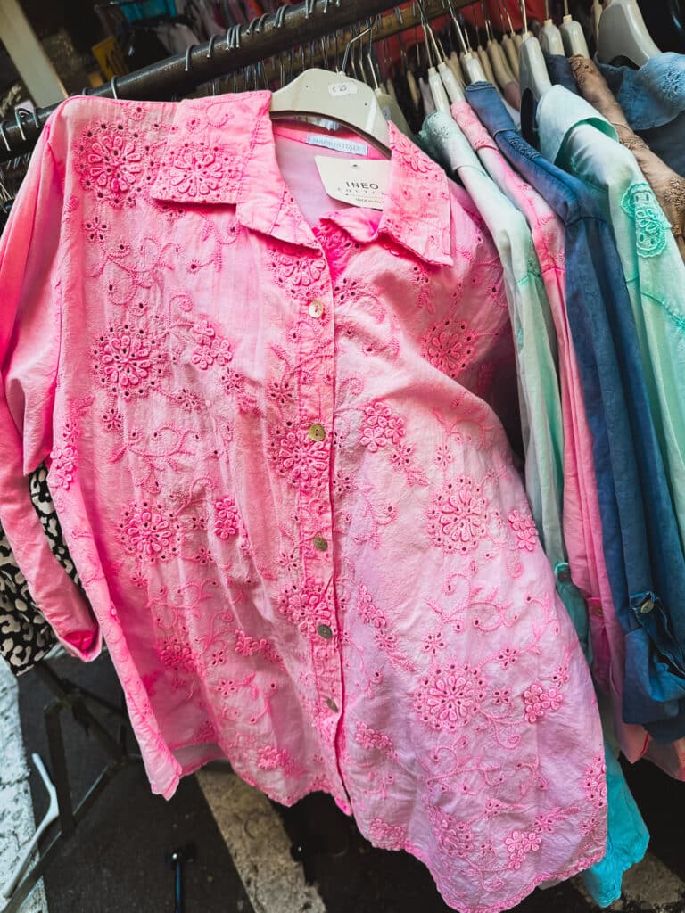 Pink linen shirt hanging on a clothing rack at the Pernes-les-Fontaines market.