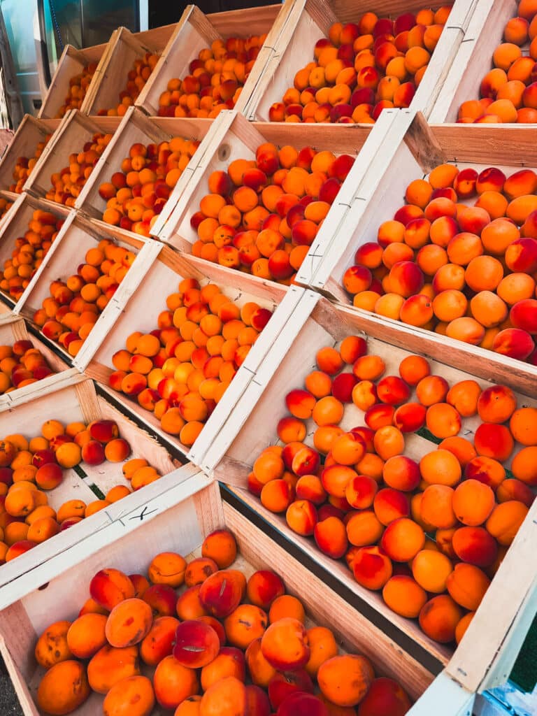 Crates of ripe peaches and apricots stacked at a Provençal farmers market.