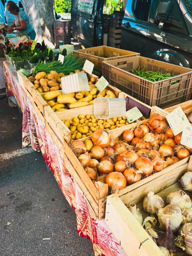 Market table piled with potatoes and onions at the Saturday market in Pernes-les-Fontaines.