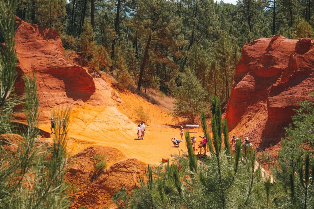 Entrance section of Le Sentier des Ocres trail in Roussillon with a boardwalk through bright orange rock formations.