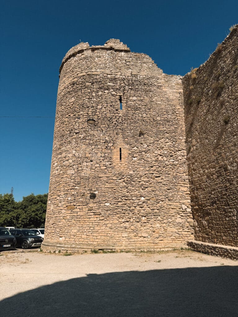 Close-up view of Venasque’s medieval stone ramparts and Sacaren tower against a deep blue sky.