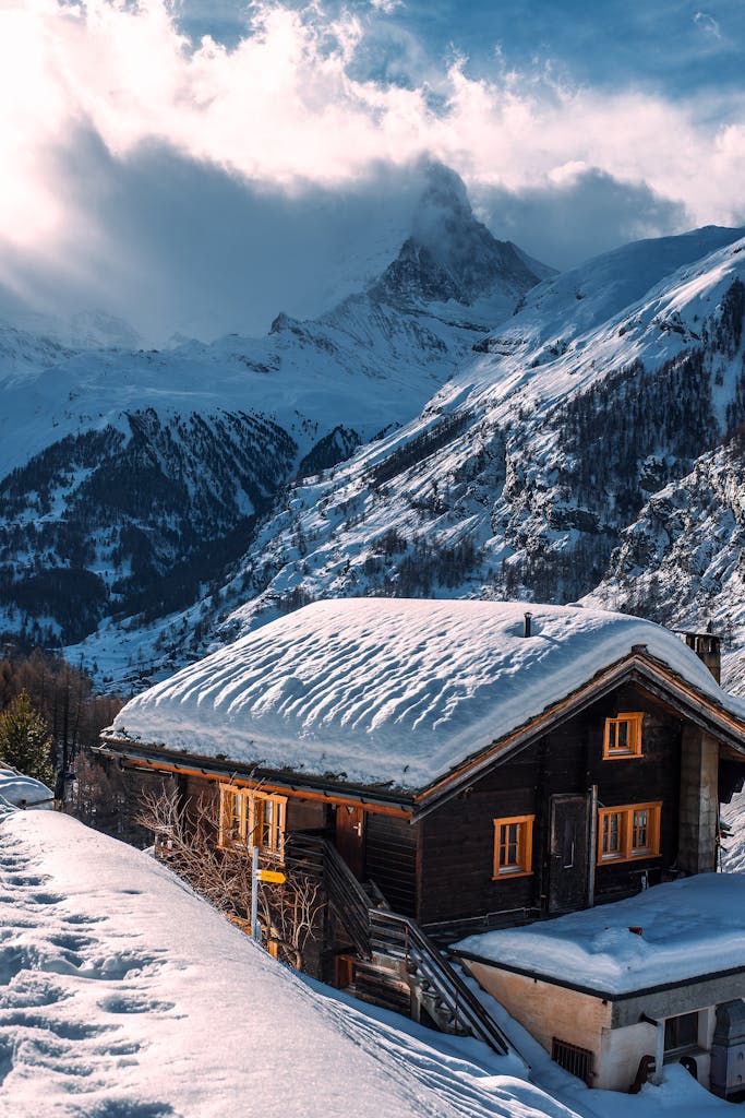 Charming snow-covered chalet set in a serene alpine mountain winter scene.