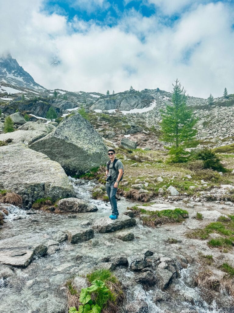A hiker standing in a stream crossing along the Grand Balcon Nord in Chamonix