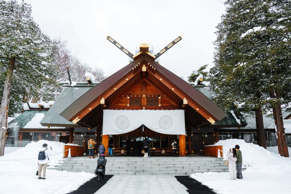 Front-on view of the Hokkaido Jingu main hall and steps surrounded by fresh snow.