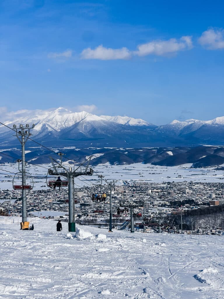 Panoramic view over the Japanese town of Furano and valley with snowy mountains rising in the distance.