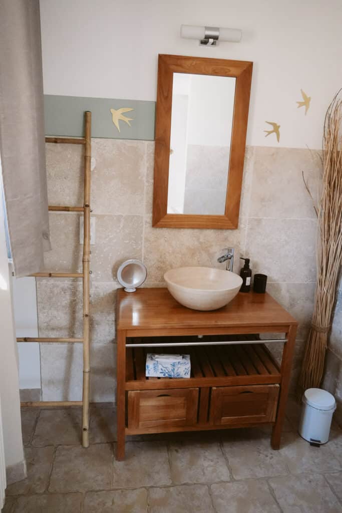 Wooden dresser and mirror with minimalist décor in a guest room at Le Temps Suspendu Provence.