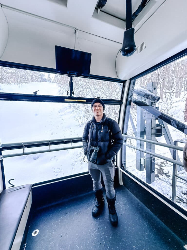 ravel Buddy standing inside the Mt. Moiwa ropeway gondola above snowy forest.