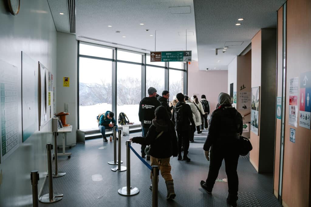People waiting inside the Mt. Moiwa summit station near large windows.