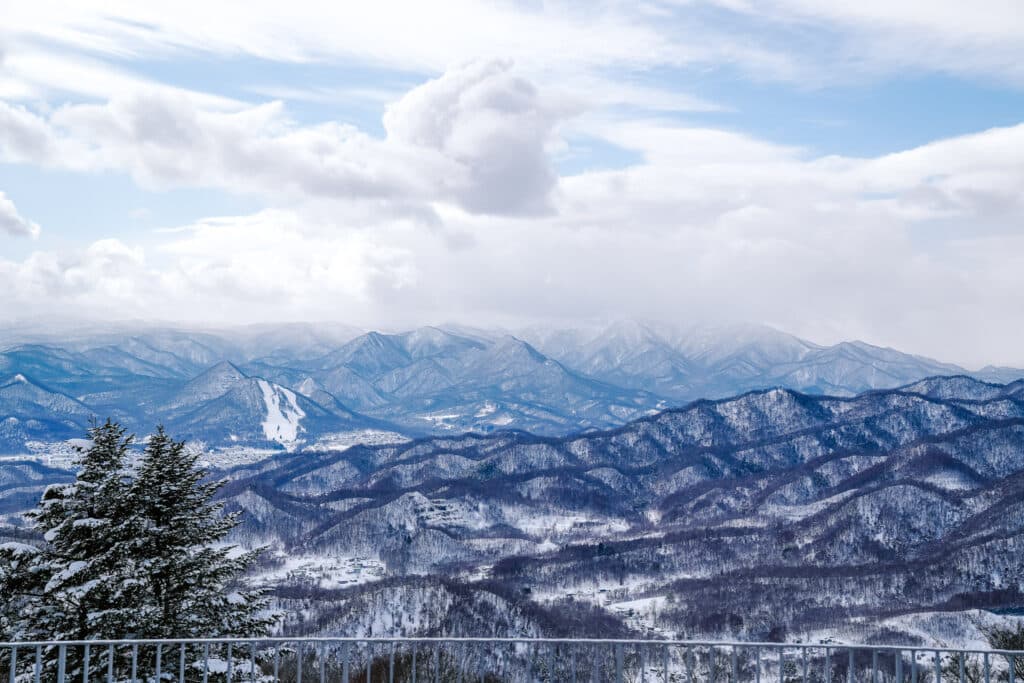 Wide mountain panorama from Mt. Moiwa with snow-covered peaks and dramatic clouds.