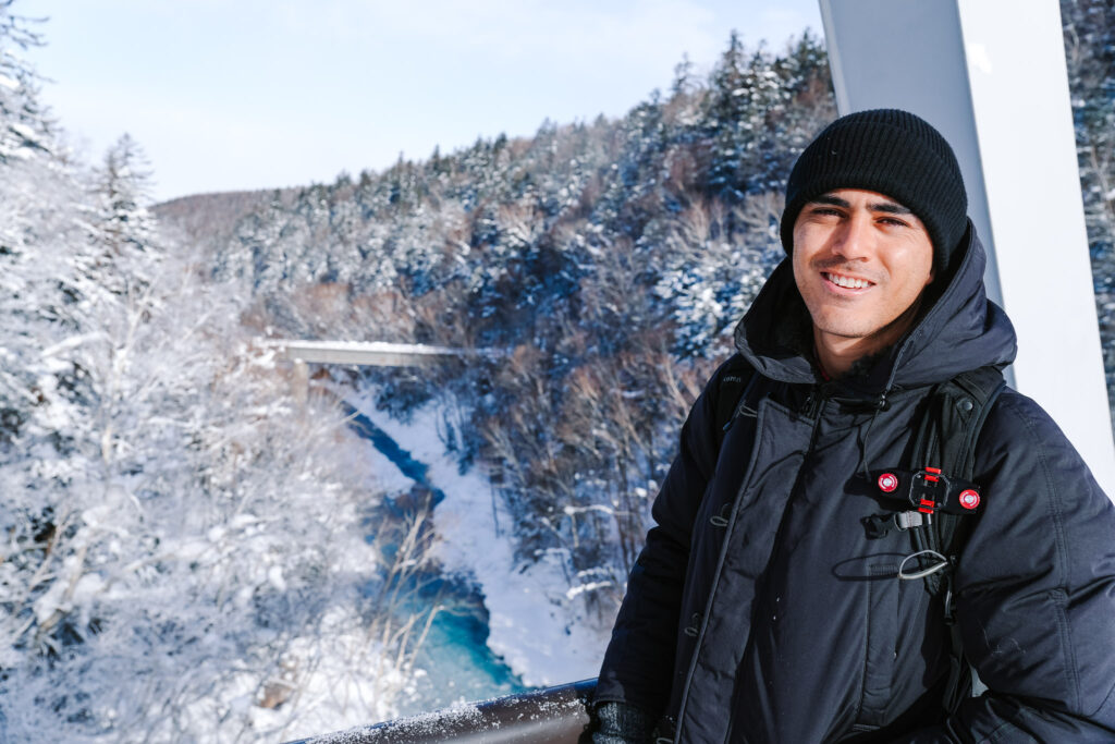 Traveler smiling on the bridge in front of the Shirahige Waterfall