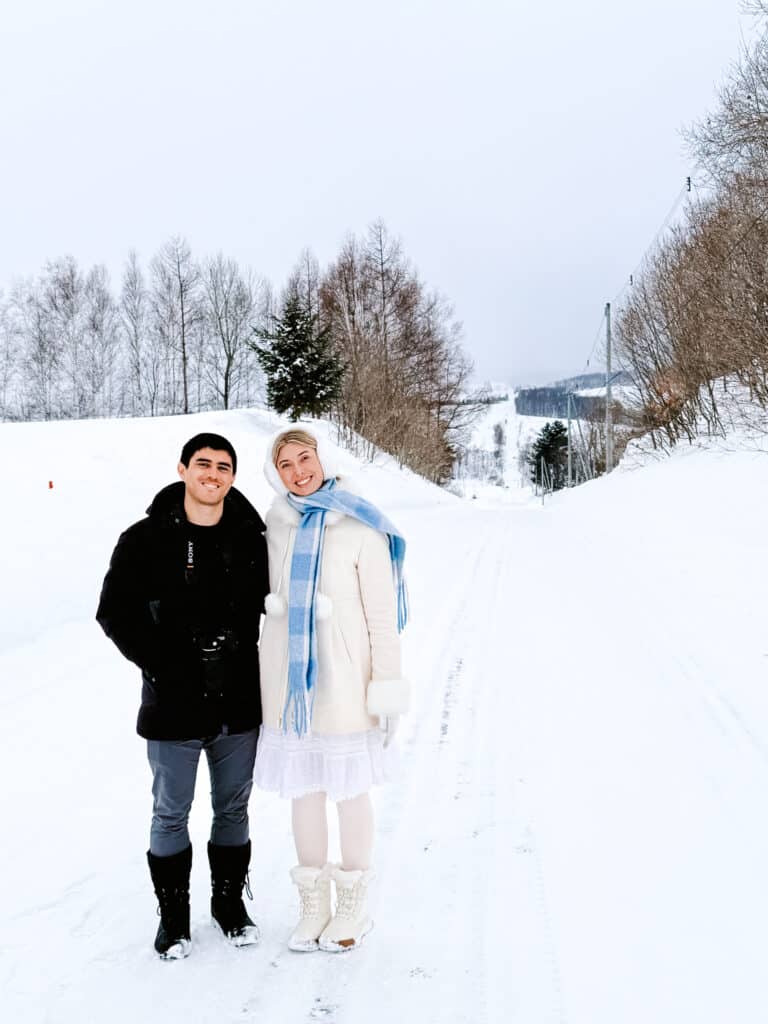 Couple posing together on the snowy Roller Coaster Road on the Biei Patchwork Hills road trip in Hokkaido