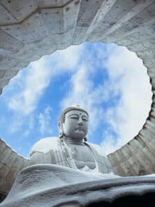 Buddha statue framed by a circular opening to the sky at the Hill of the Buddha shrine in Sapporo.