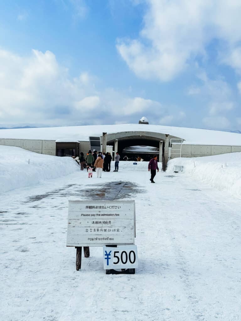 Entrance to the Hill of the Buddha rotunda at Makomanai Takino Cemetery in Sapporo with visitors walking up the snowy path