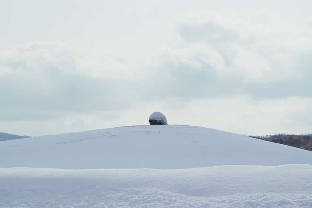 Snow-covered hill with the Buddha’s head rising above the landscape at the Hill of the Buddha shrine in Sapporo.