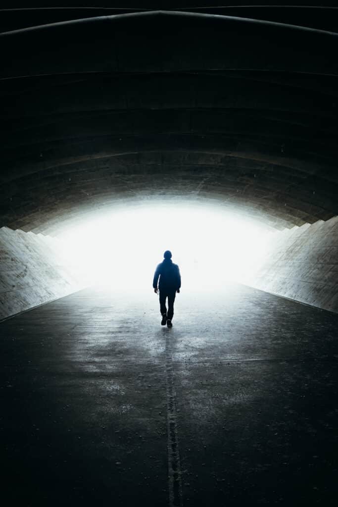 Silhouette of a visitor walking through the concrete tunnel toward the Hill of the Buddha shrine in Sapporo.
