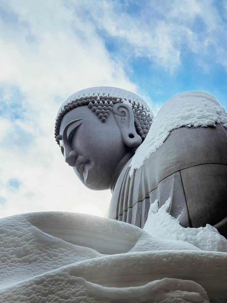 Snow-covered Buddha statue inside the circular rotunda at the Hill of the Buddha in Sapporo during winter.