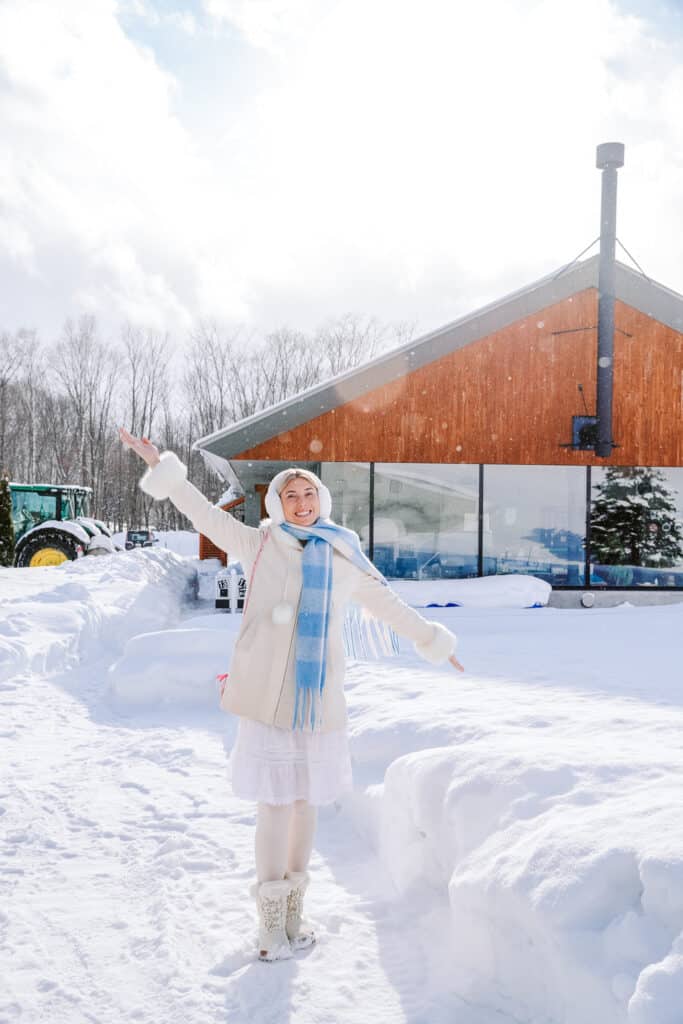 Happy visitor posing in the snow outside La Laiterie Ferme Biei on a bright winter day