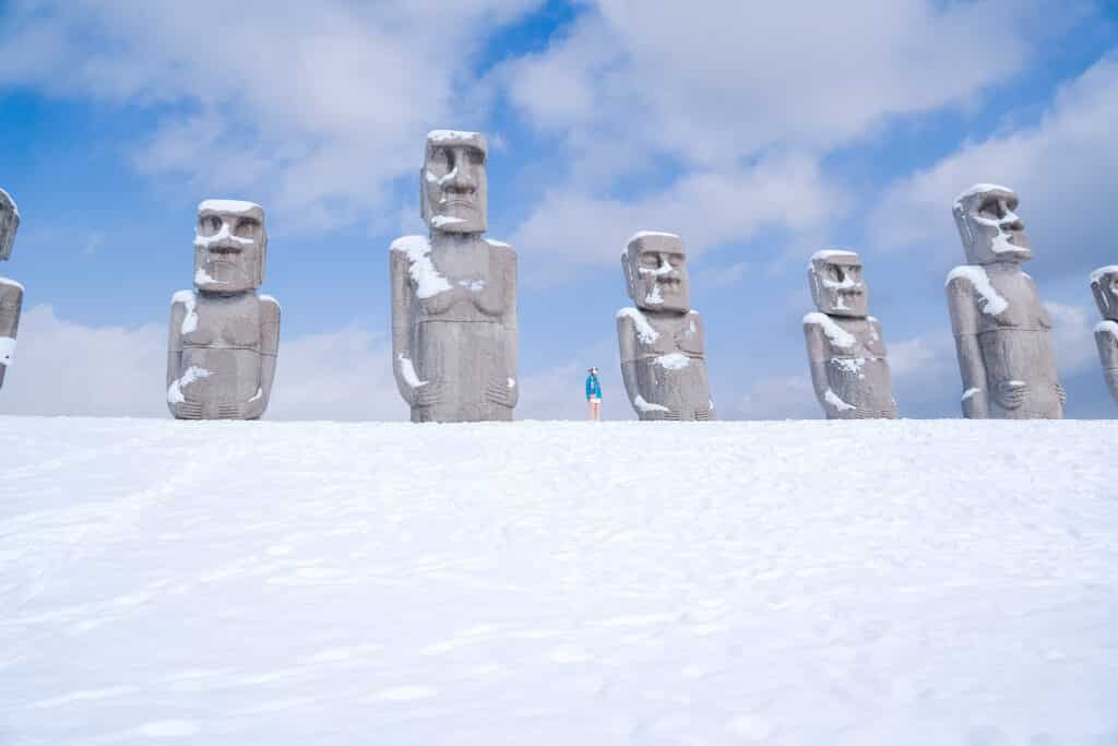 Wide view of Moai statues in winter snow under blue sky at Makomanai Takino Cemetery in Sapporo