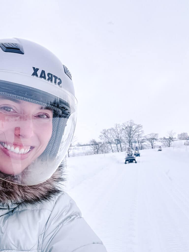 Smiling rider in helmet taking a selfie during a snowmobile tour at Snow World Toya