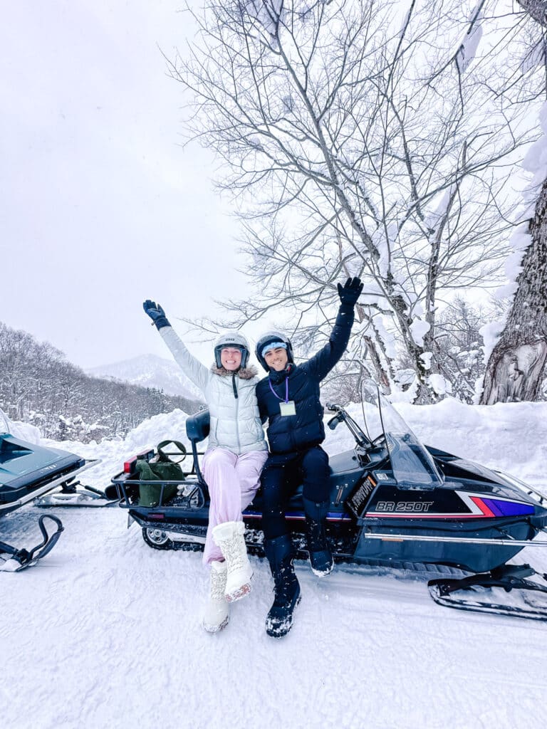 Visitors posing with snowmobiles during a scenic stop near Lake Toya