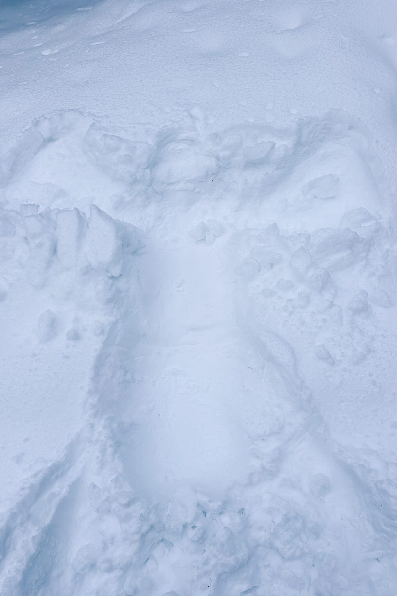 Snow angel imprint in deep powder during a winter snowshoeing tour