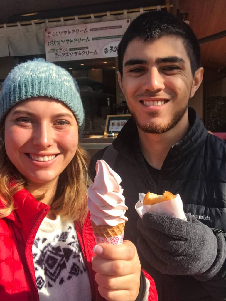 Two travelers holding sakura flavored soft serve ice cream and a potato croquette