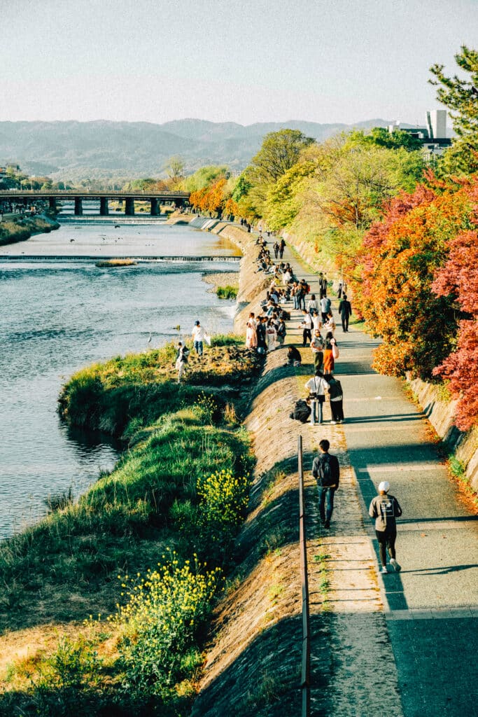 People walking along the Kamogawa River in Kyoto