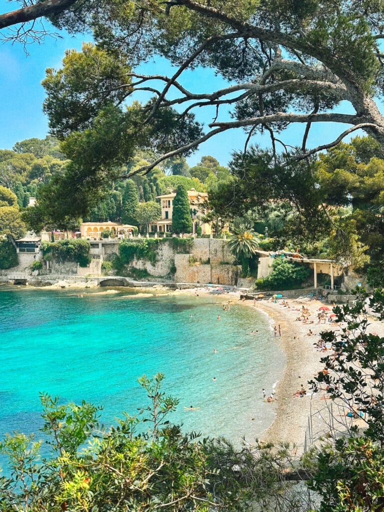 Wide view of Plage de la Scaletta with turquoise water, curved shoreline, and coastal greenery